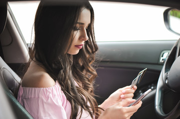 Young business woman sitting in car using mobile phone