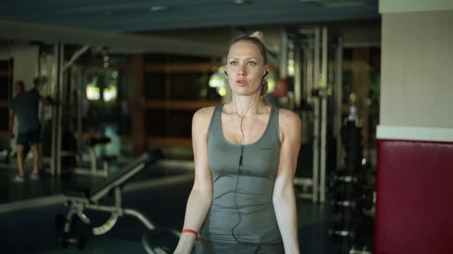 Attractive woman exercising with dumbbells. The blonde trines the biceps. Girl at the fitness club.