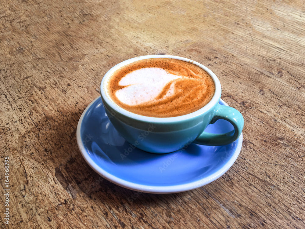 Poster Coffee cup with heart pattern  in coffee shop on wooden table with vintage style effect, close up with copy space .