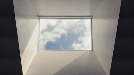 Modern interior skylight showing grey sky and misty clouds. Black and white skylight in modern office building. Abstract, artistic image of sky and clouds