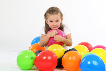 Kleines Mädchen sitzt zwischen Luftballons