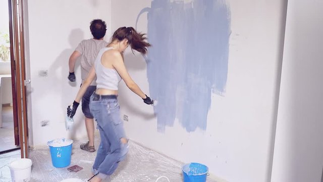 Funny couple dancing happy while painting wall in new home  4K