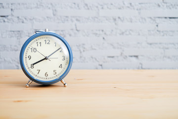 vintage clock on the wood table on brick wall background