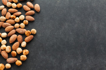 Assortment of nuts on black background with free space for text. Healthy snack for keeping you in good shape. Perfect to eat with beer.