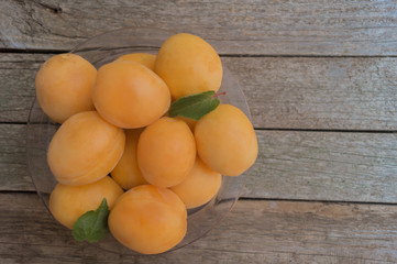 Ripe orange apricots in the plastic plate on grey wooden background