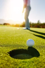 Deurstickers Golf Golfbal aan de rand van het gat met speler op de achtergrond