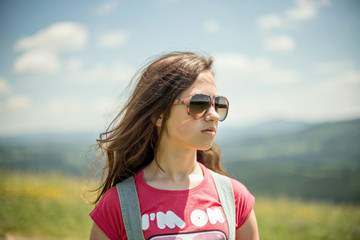 Young girl in sunglasses against the background of mountains