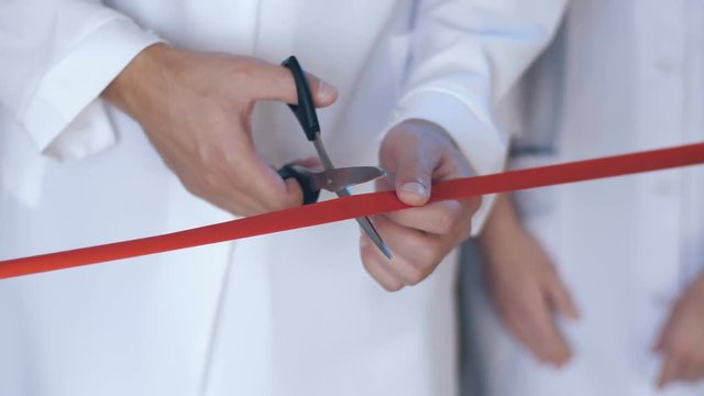 Architect cutting red ribbon at official opening of new construction