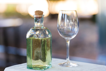 A bottle of water and a wineglass on the table. Close-up.