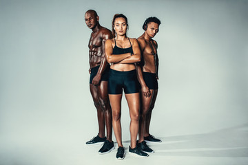 Group of muscular people standing on grey background - Powered by Adobe