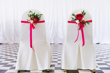 Bridal chairs decorated with flowers.
