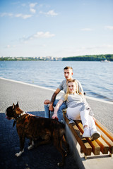 Couple in love with two dogs pit bull terrier against beach side.