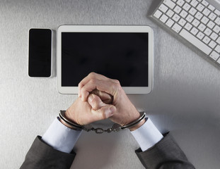 restrained businessman fists tied with handcuffs facing digital technology