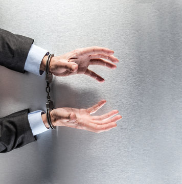 desperate businessman with handcuffs begging and complaining at the office