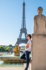 Cheerful handsome young tourist man taking pose in front of the Eiffel tower in Paris