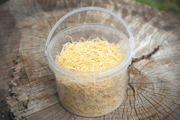 Homemade noodles in a plastic box isolated on wooden background