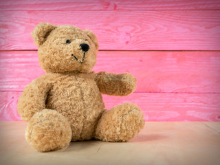 Teddy bear with pink wooden background.