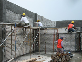 Construction workers plastering building wall and beam using cement plaster mix of cement and sand...
