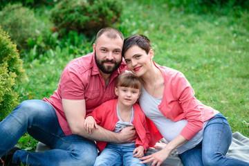 Fototapeta premium Happy family walking in the park. Pregnancy.