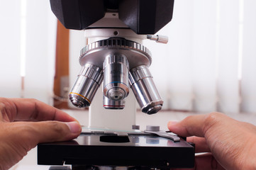 Doctor hand work with microscope in laboratory room. Scientific research.