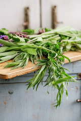 Assortment of fresh herbs mint, oregano, thym, blooming sage on cutting board over old blue white wooden kitchen table. Rustic style, day light.