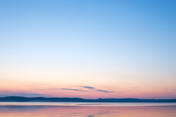 soft and calm sunset at Balaton lake in summer - thin clouds, velvet sky and hills in background