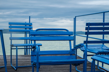 blue chairs on dock or pier waiting for turist - cloudy sky cold weather at Balaton lake in the summer season