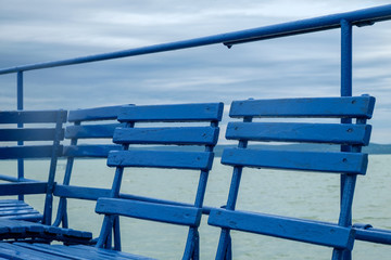 blue chairs on dock or pier waiting for turist - cloudy sky cold weather at Balaton lake in the summer season
