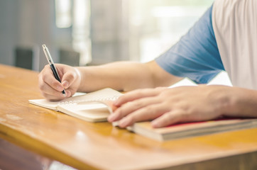 Close up of student hand writing on book with pen
