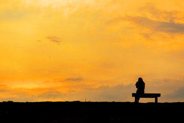 Obraz premium silhouette of woman relax on chair happy time sunset