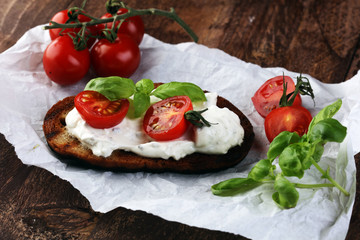 Bread with cream cheese and tomato for lunch table. Sharing antipasti on party or summer picnic time over wooden rustic background.