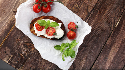 Bread with cream cheese and tomato for lunch table. Sharing antipasti on party or summer picnic time over wooden rustic background.
