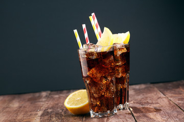 Softdrink with ice cubes, lemon and straw in glass