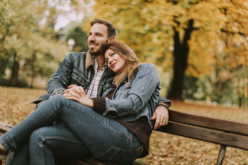 Young loving couple on the bench in the autumn park