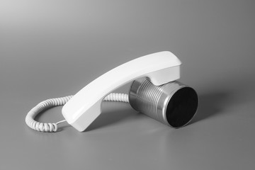 Tin can phone with handset on gray background.