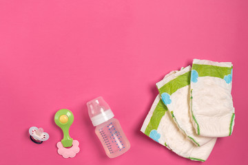 Baby care accessories and diapers on pink background. Top view