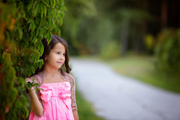 A cute little girl smiling propelling looks into the distance. Summer photo, close up.