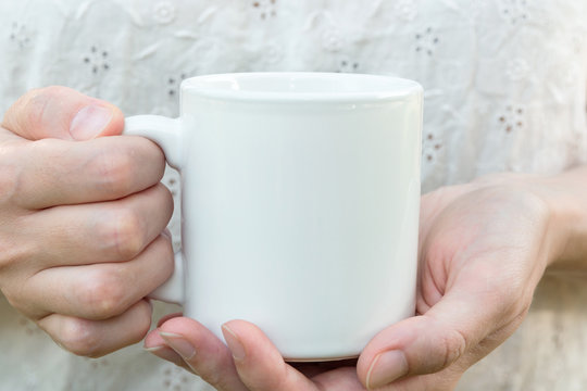 Young caucasian woman holding a white mug, mock up, blank space for text, artwork, hands, linen shirt, natural authentic, kinfolk style, soft light