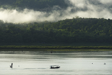 Obraz na płótnie Canvas View of the lake with a boat roaming in Kanchanaburi, Thailand.