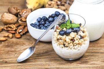 Healthy breakfast: oat granola with yogurt and fresh blueberries on wooden background