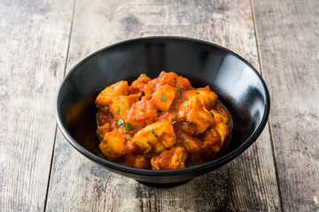 Chicken tikka masala in black bowl on wooden table
