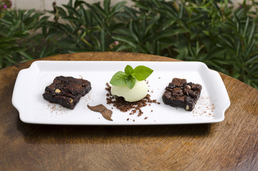 Brownie pie with pistachio ice cream on a white plate