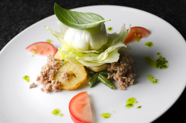 Mix salad with egg poached and tuna on a white plate