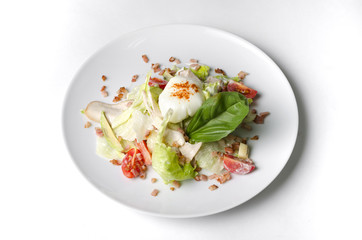 Mix salad with egg poached and chicken on a white plate