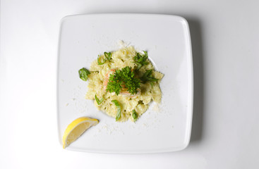 Farfalle with shrimps and pesto sauce on a white plate
