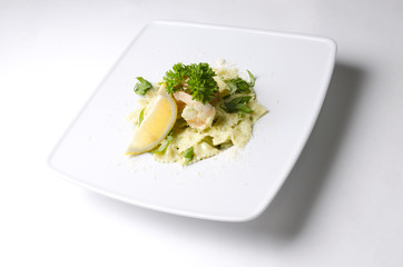 Farfalle with shrimps and pesto sauce on a white plate