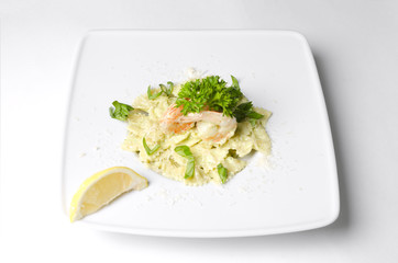 Farfalle with shrimps and pesto sauce on a white plate
