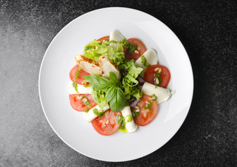 Salad with tomatoes basil and mozzarella with croutons on a white plate