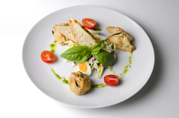 Salad with pies and lettuce leaves on a white plate