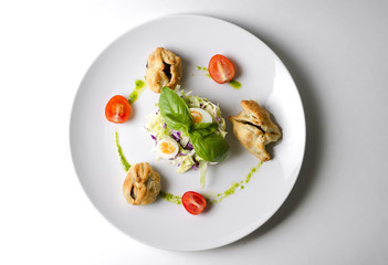 Salad with pies and lettuce leaves on a white plate
